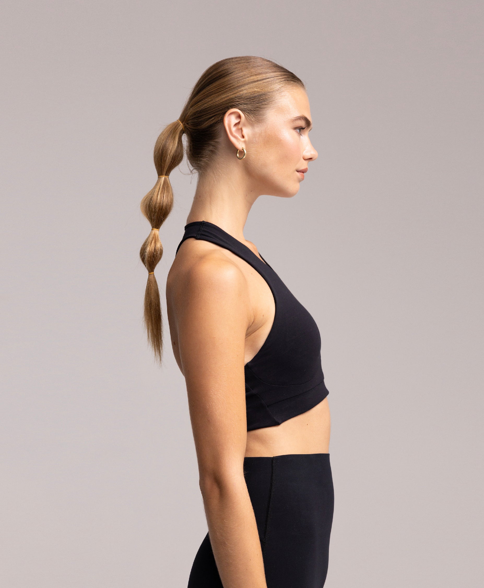 Side view of the Philos Running bra in black, which features a high neck and racerback design, medium support, and laser-cut hems.