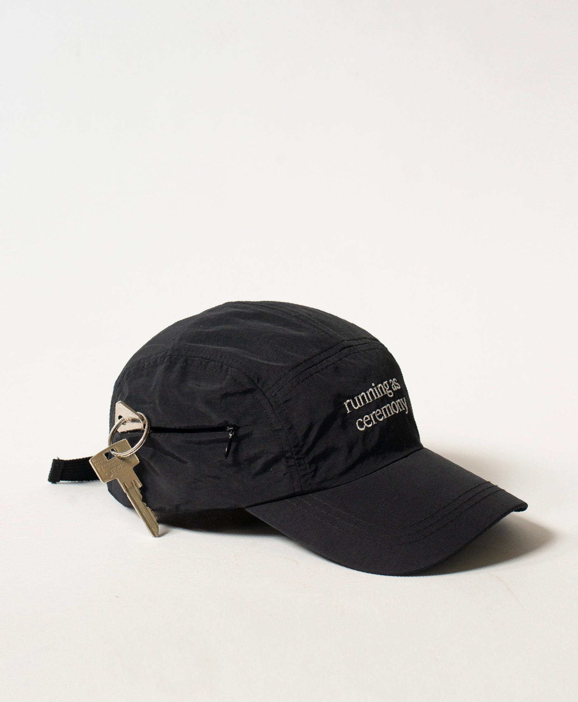 Side shot of the Philos Running Cap in black, featuring white text that reads