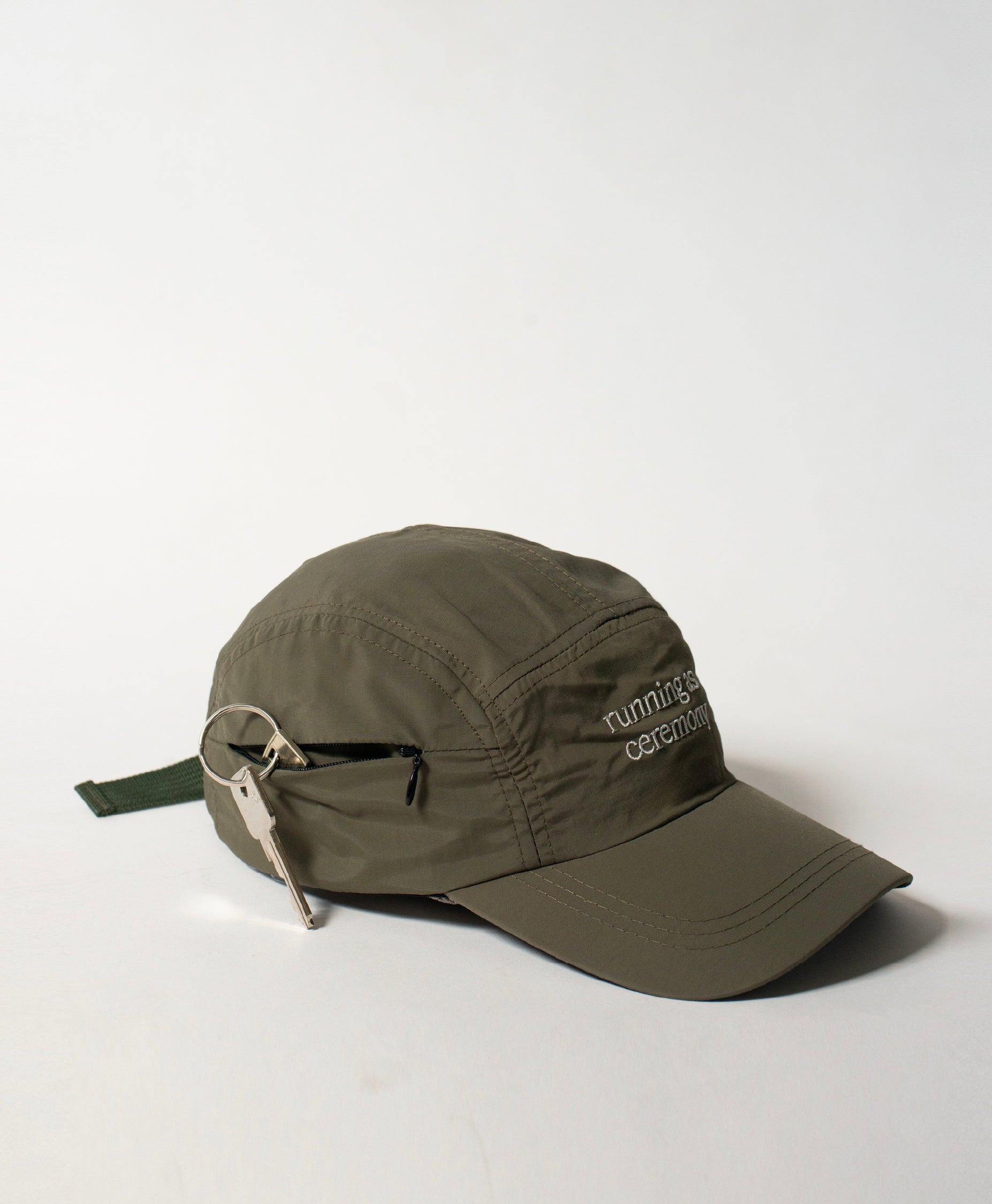 Side shot of the Philos Running Cap in olive green, featuring white text that reads