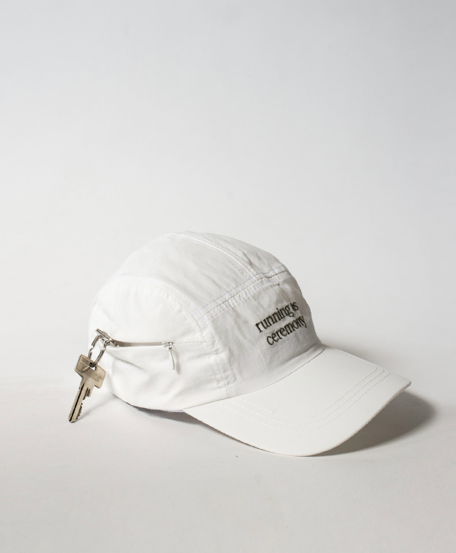 Side shot of the Philos Running Cap in white, featuring gray text that reads