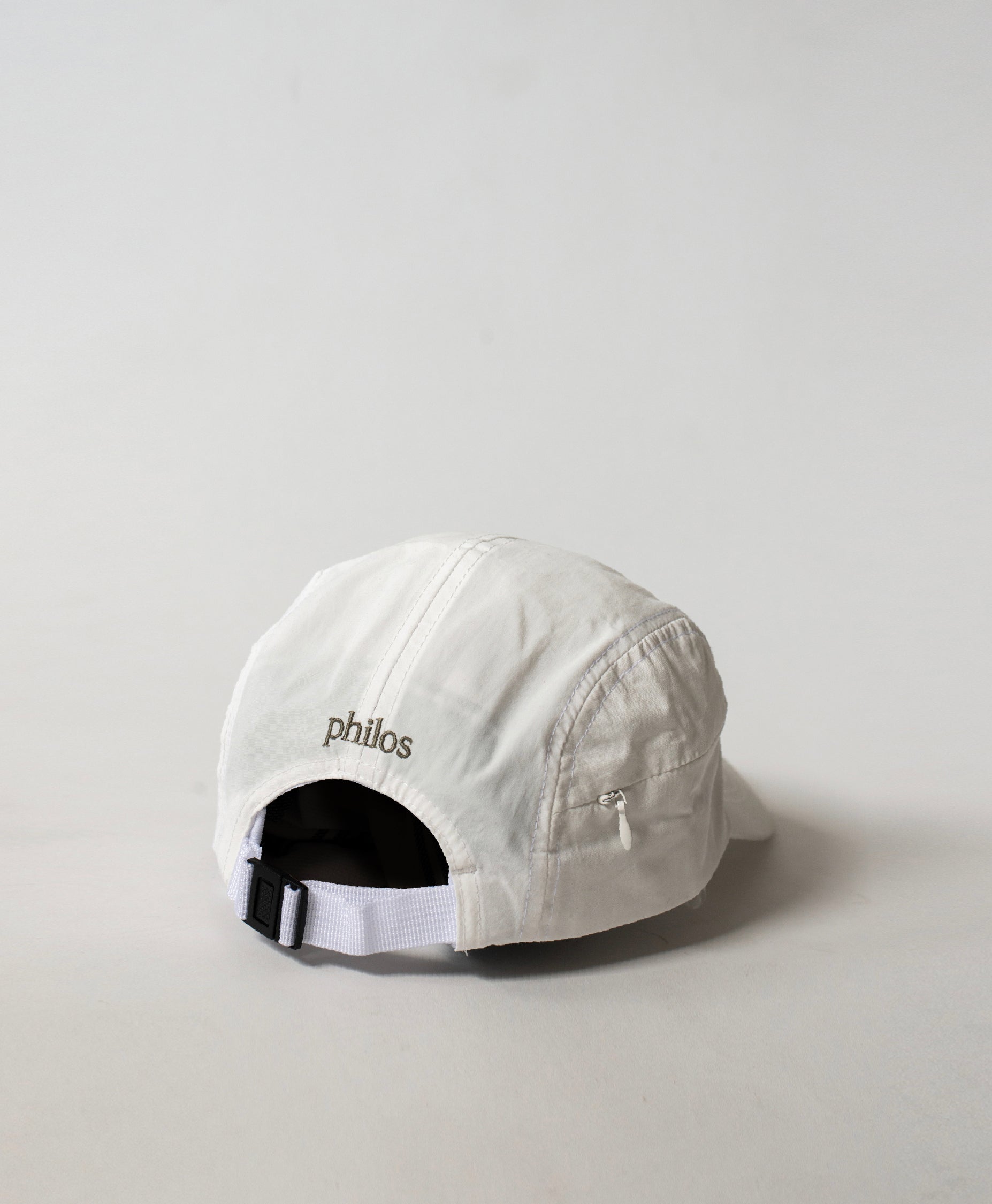 Back view of the Philos Running Cap in white, featuring an adjustable strap for a customizable fit and a discreet key pocket with a zipper.