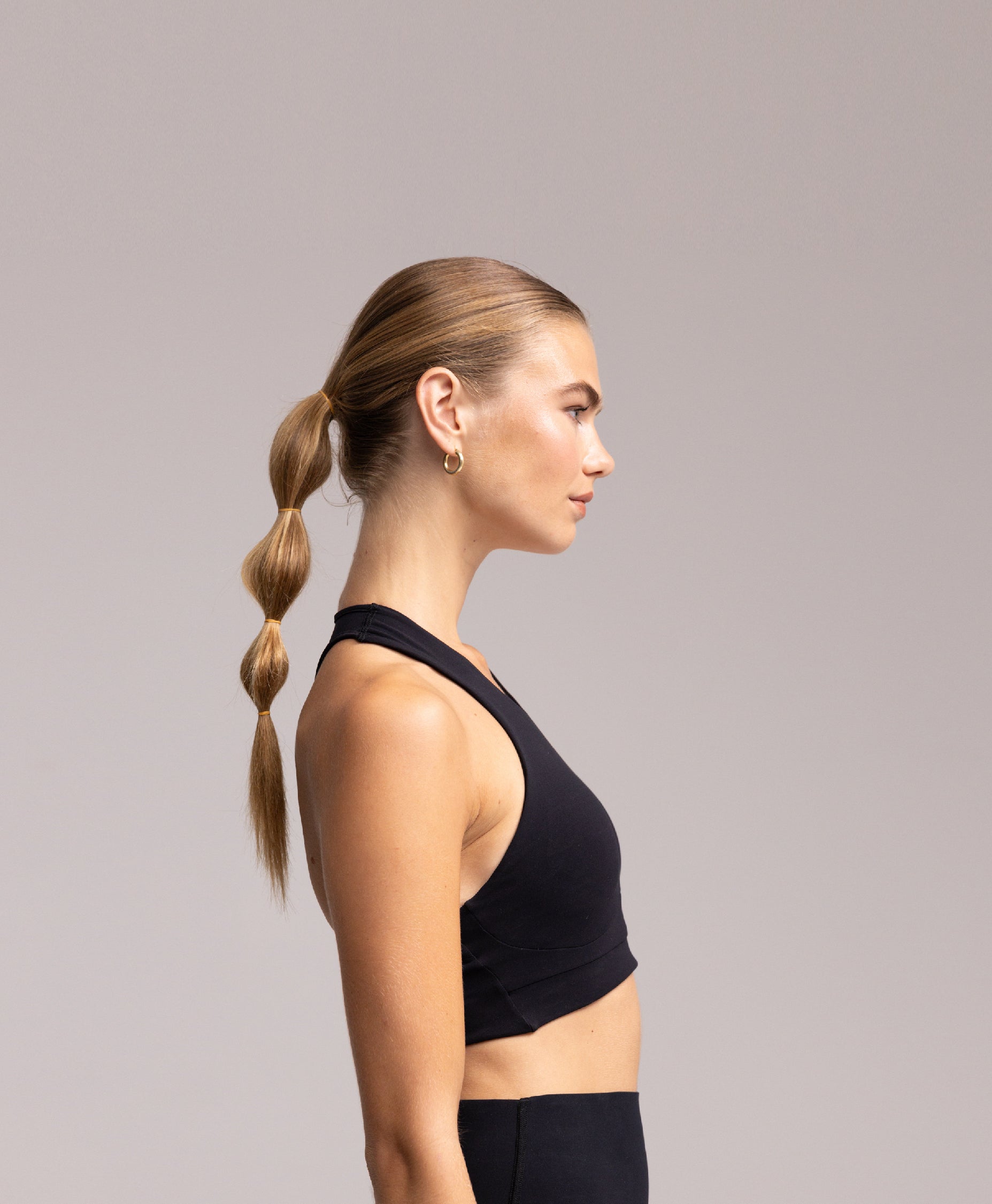 Side profile of a model wearing the Philos Armor Running Bra, emphasizing its high support and removable padding for comfort.