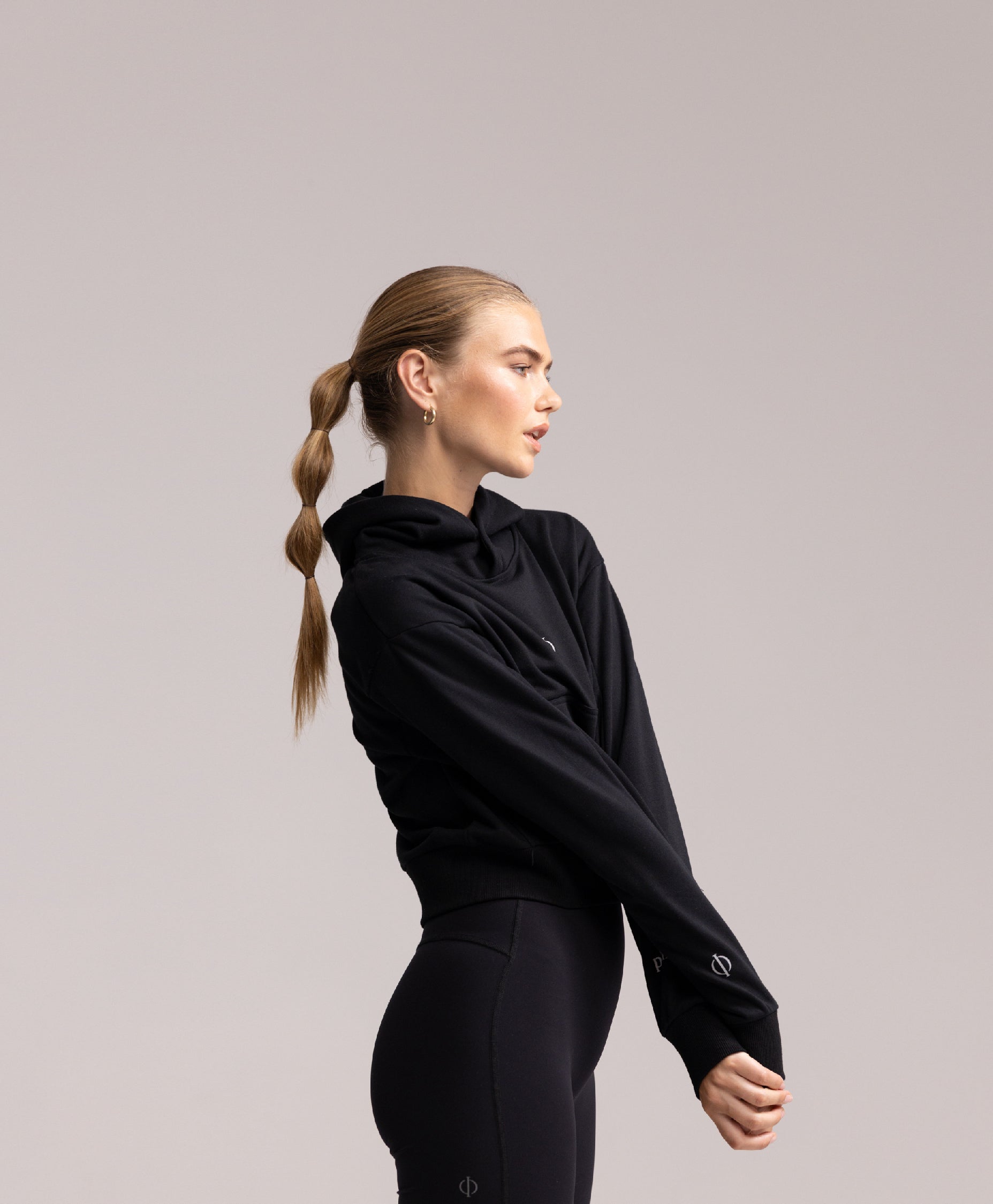 Side profile of a model wearing the Philos Armor Running Hoodie, emphasizing the thumbholes for added warmth and sleeve stability.