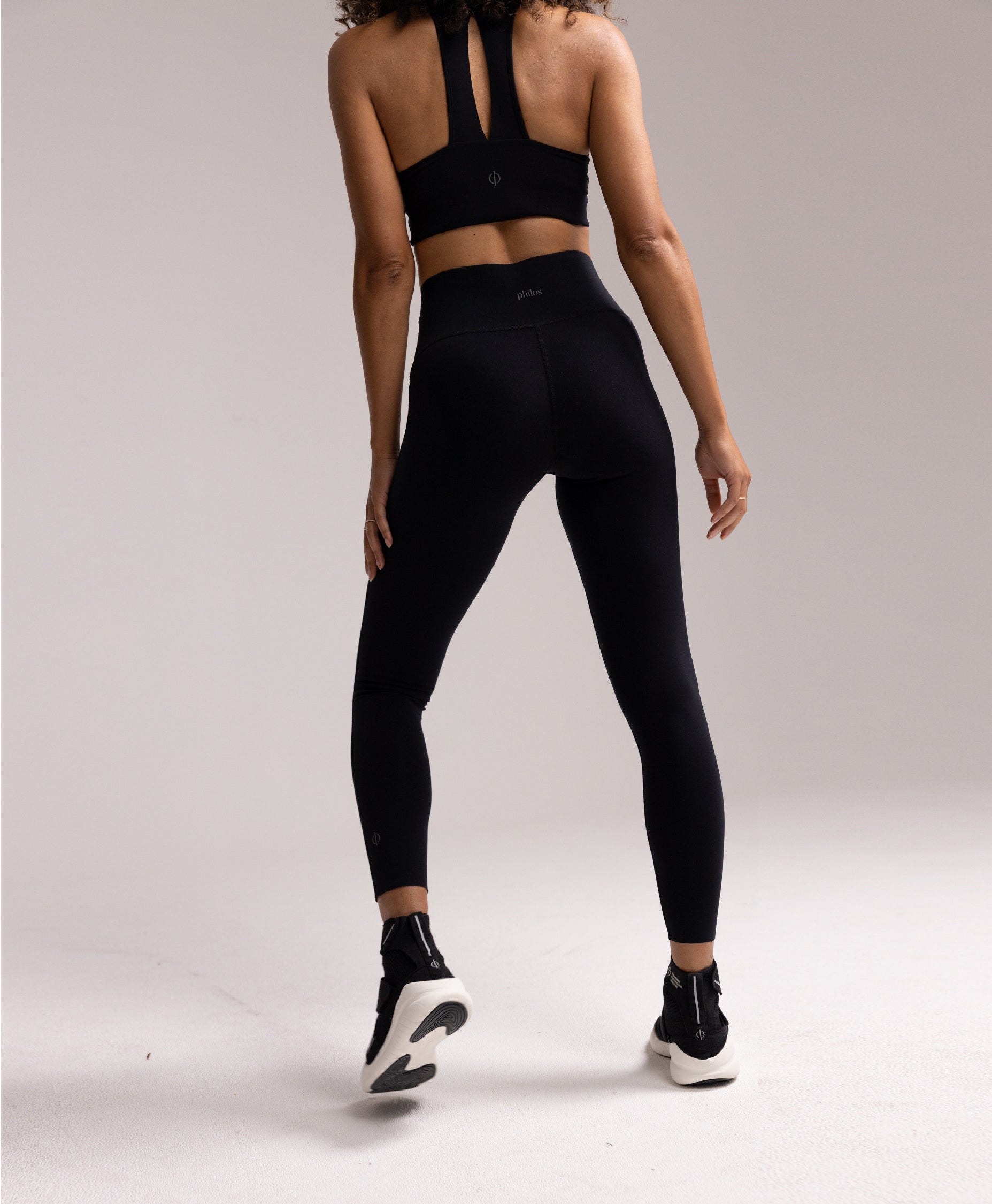 Back view of the Philos Armor Running Tights, highlighting the high-waisted design, reflective logos for visibility, and laser-cut hems for a sleek look.